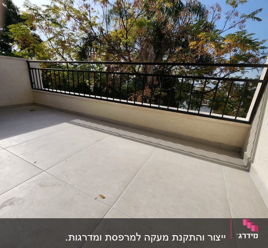 מעקה מתכת שחור על מרפסת מרוצפת